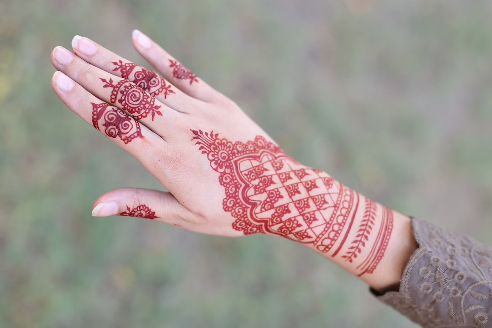Back hand mehandi in red-brown tone featuring a clean lattice grid, floral lace edging, and simple finger details