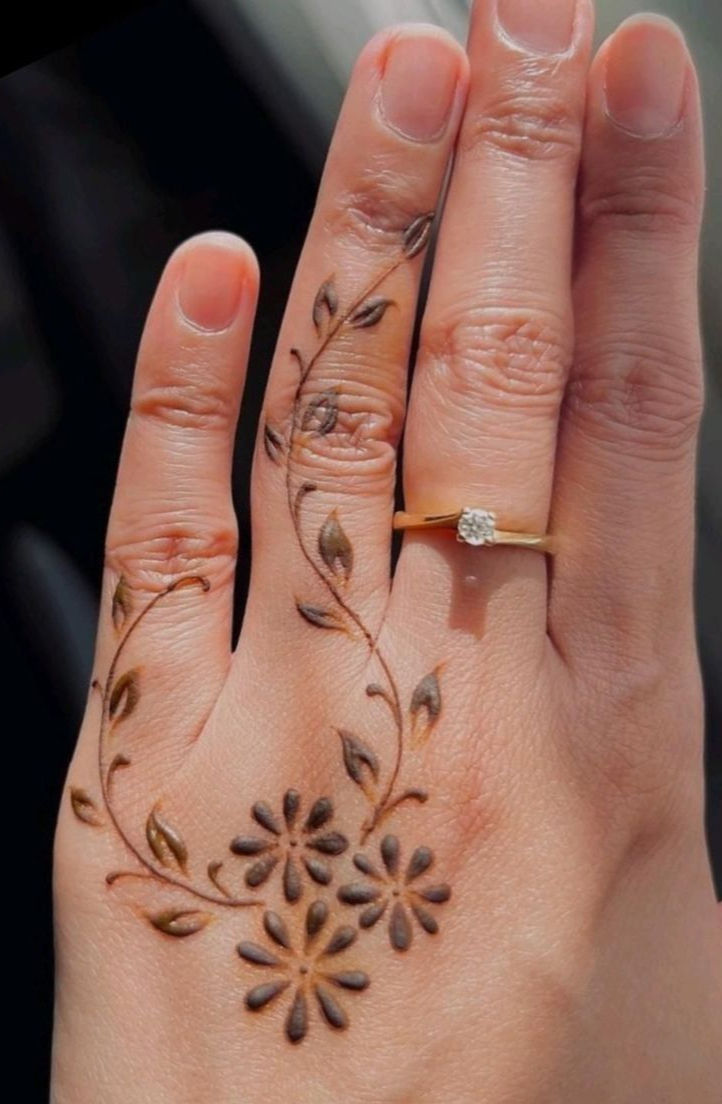 Floral mehndi on fingers with a gold ring.