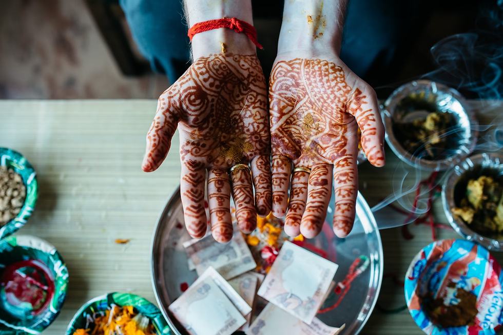 Hands extended over a puja thali, decorated in traditional front hand mehndi