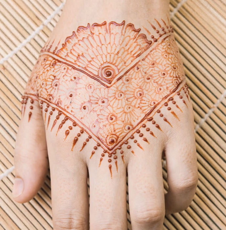 Back hand mehndi design with V-shaped border, floral filling, and a bold fan-like motif at the wrist