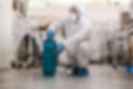 worker-in-protective-uniform-with-mask-and-rubber-gloves-crouching-and-spraying-with-disin