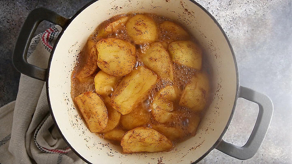 A large pot of apples and cinnamon bubbling in a brown liquid.
