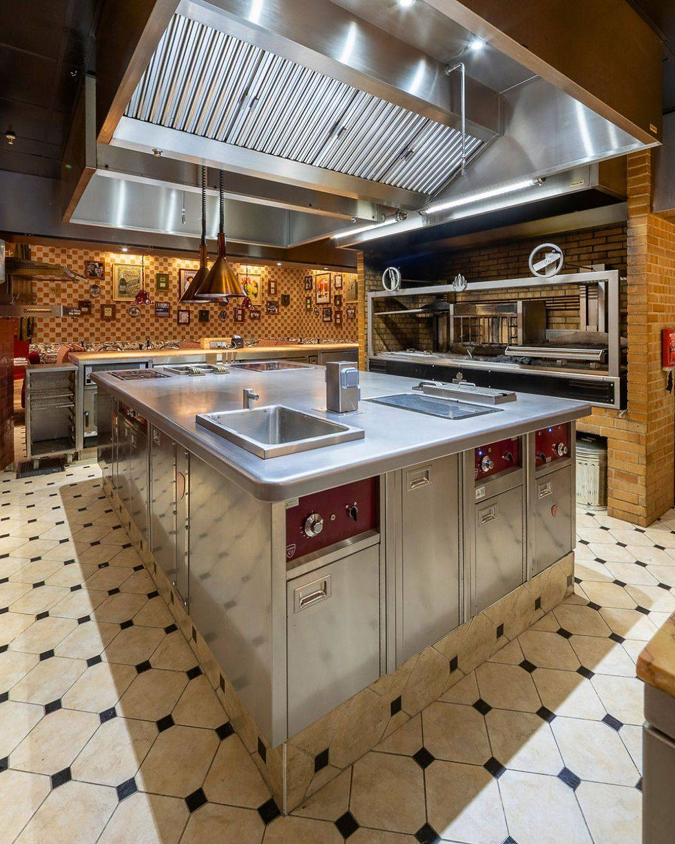 Chef préparant des plats dans une cuisine professionnelle avec des appareils en acier inoxydable.