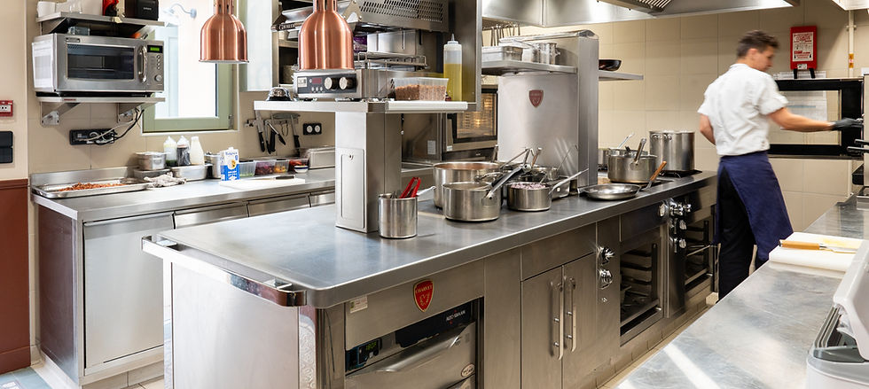 Chef préparant des plats dans une cuisine professionnelle avec des appareils en acier inoxydable.