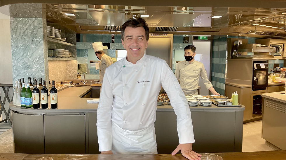 Chef de cuisine souriant dans sa cuisine, autres chefs en arrière-plan, décor de restaurant.