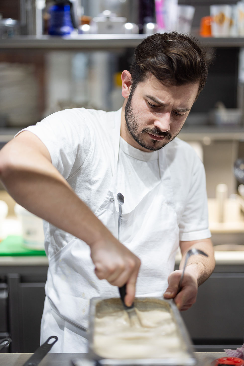 Chef cuisinier dans une cuisine professionnelle. Il porte un tablier blanc et est entrain de travailler.