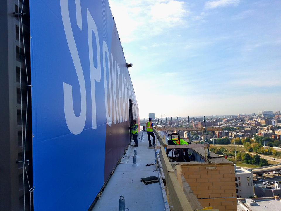A large rooftop banner at the top of a building, advertising new building construction in Chicago, made for high visibility.