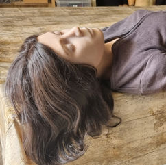Realistic female manikin with long brown hair lying on a wooden table