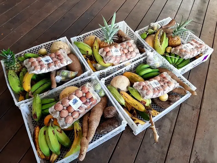 Photo of 5 white baskets filled with local produce that are sitting on a wooden floor