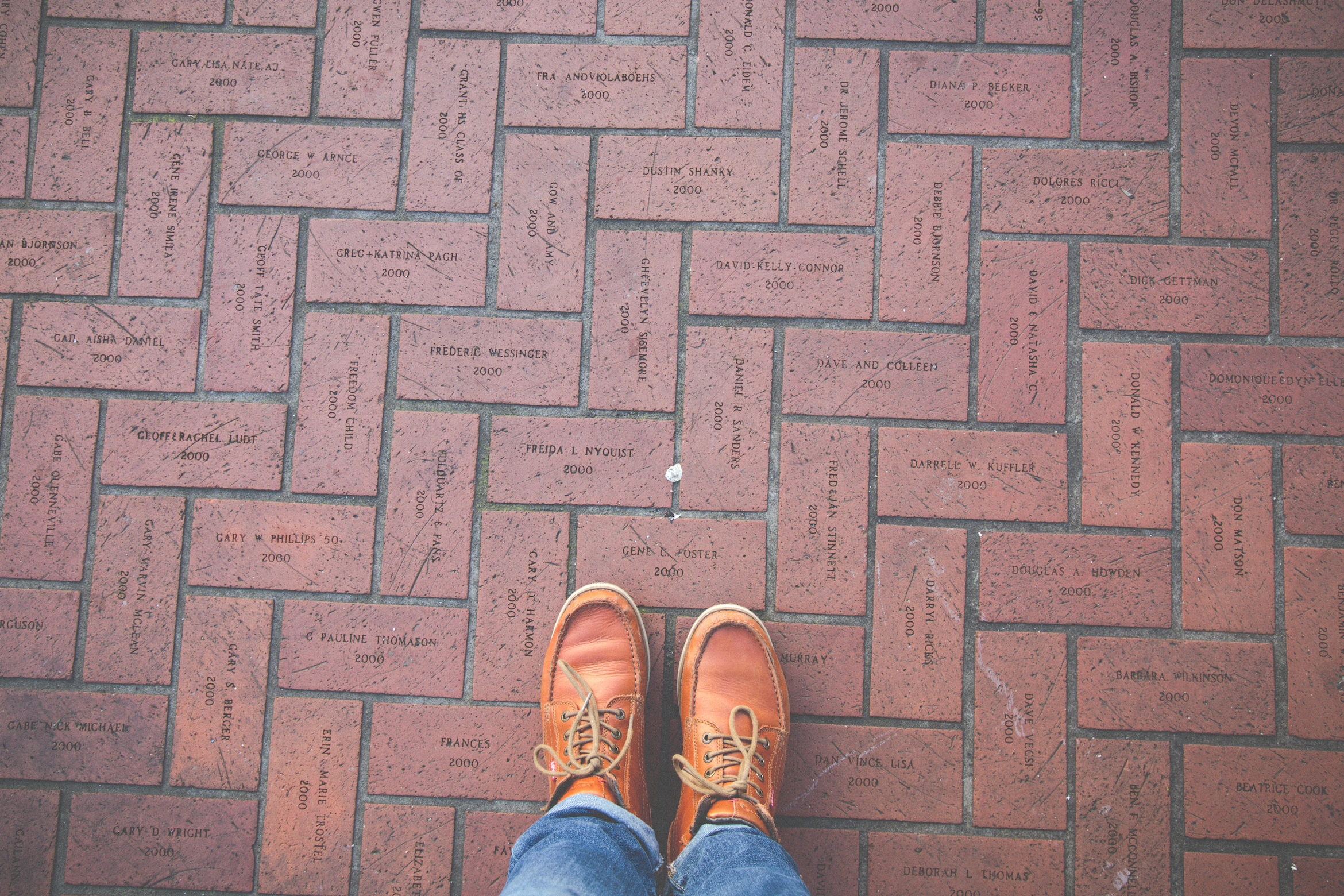 A brick walkway of names and dates, and a pair of feet.