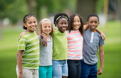 Diverse group of smiling school-age children standing outside with their arms around each other's shoulders