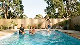 Family playing in a heated backyard pool with a child jumping in from the edge