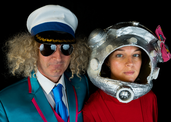 Man with captain's sailor's hat and woman in space helmet looking serious at camera