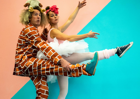 Man in brick pattern suit and women in tutu posing in a ballet pose.