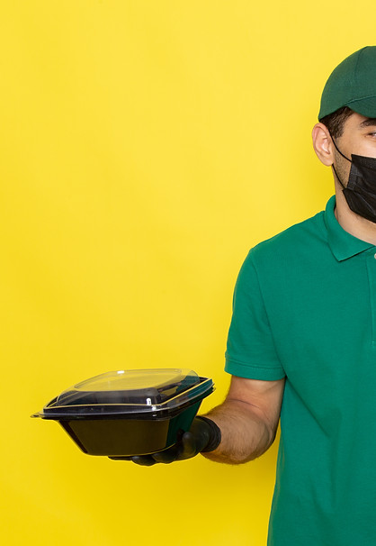 front-view-young-male-courier-green-shirt-green-cap-holding-food-bowls-black-mask-yellow-w