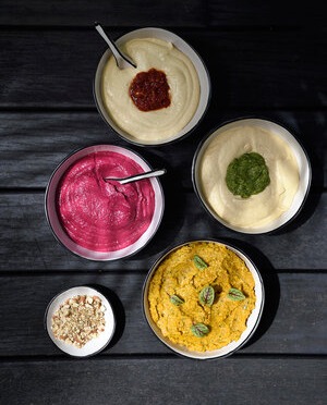 Four flavors and colors of hummus laid on table