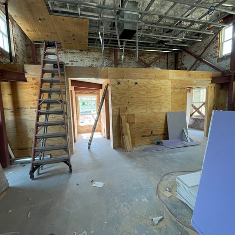 Commercial office renovation in progress with exposed concrete floors, unfinished plywood ceiling, and open wall framing in Tampa.