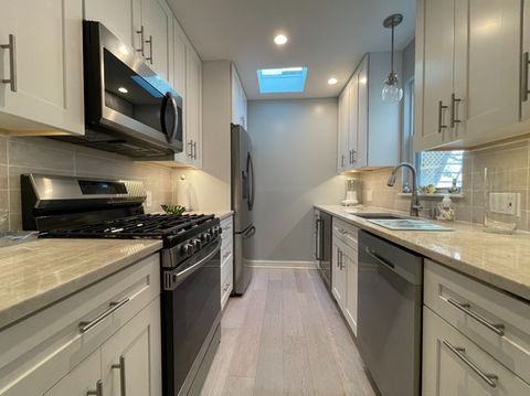 Modern kitchen renovation with white cabinetry, stainless steel appliances, and a beige quartz countertop in Tampa.