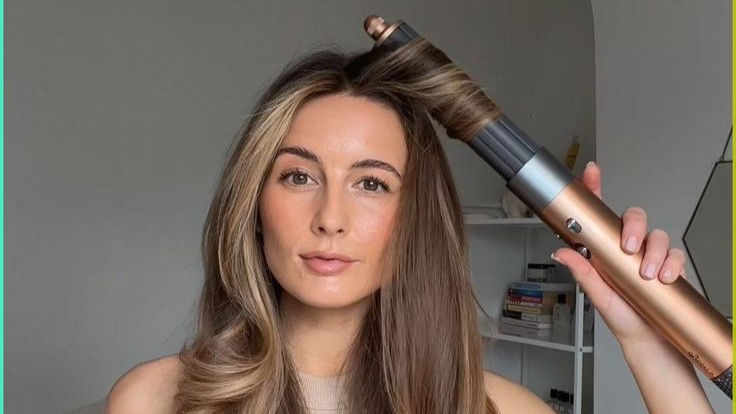 woman using a curling iron for voluminous curls