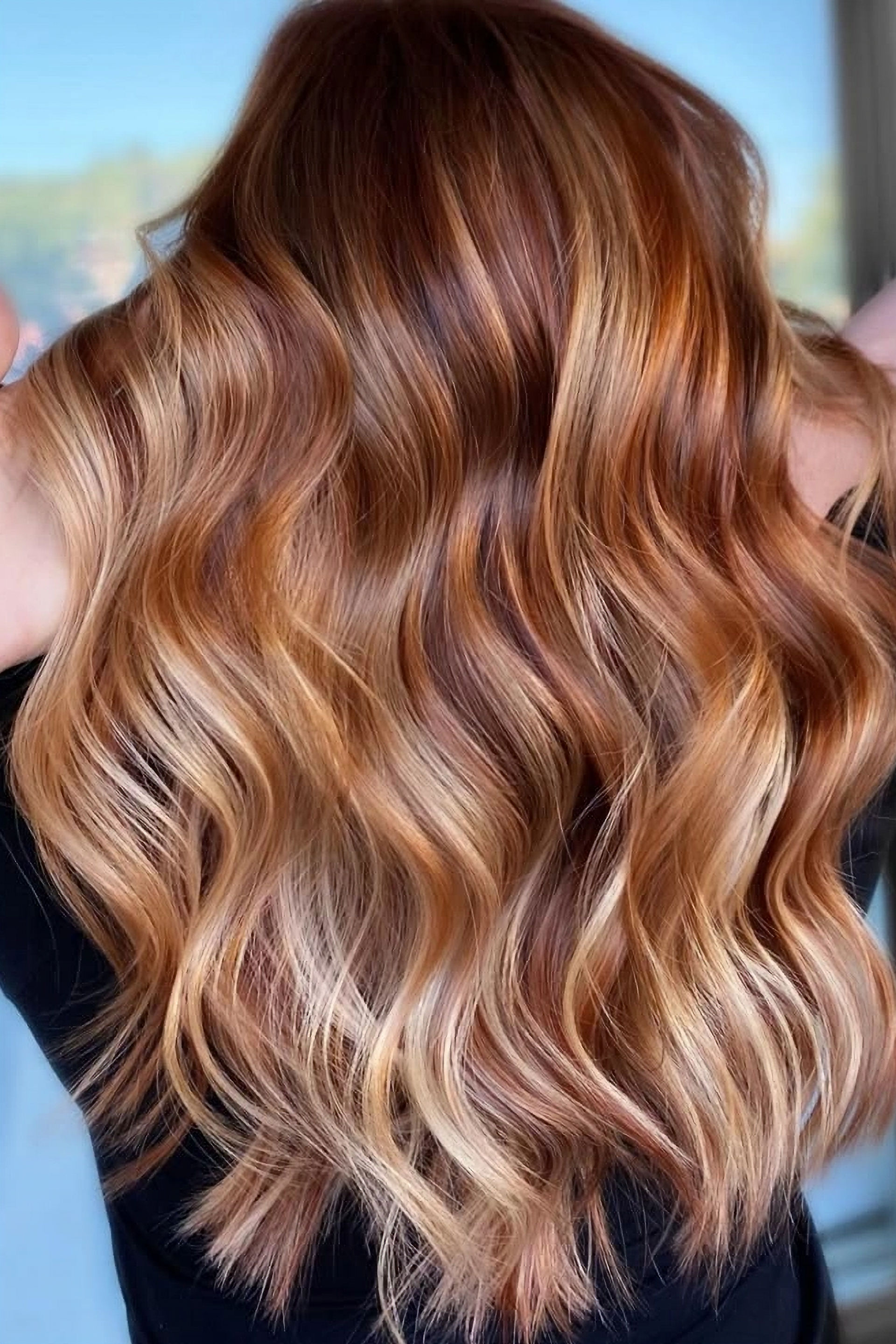 Long curled brunette hair with blond and copper balayage highlights