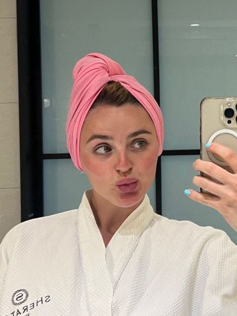 woman taking a mirror selfie in a pink HALO t-shirt hair towel styled in a turban wrap