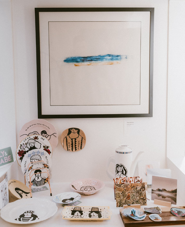Ceramic plates, bowls, teapot, and framed art on display