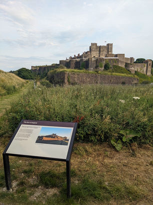 At the forefront is an interpretation panel with text and an image, while in the background is a view of Dover Castle
