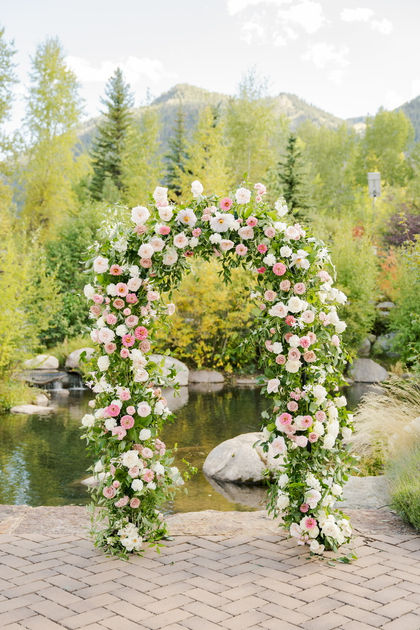 Floral arch with pink and white flowers by a pond