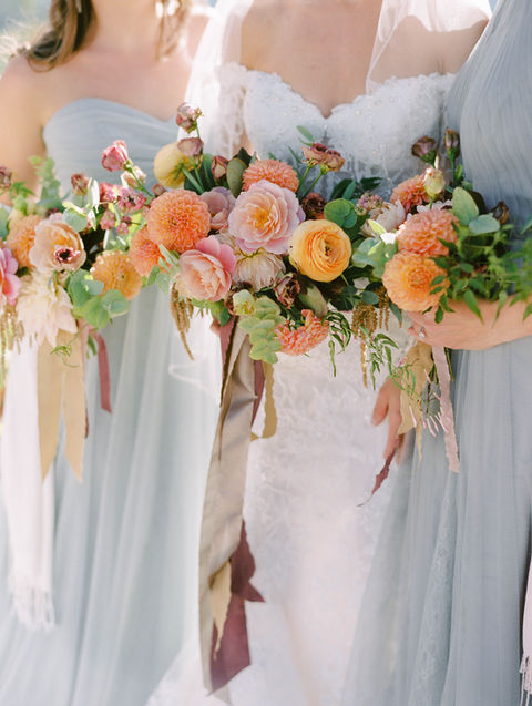 Bridesmaids in blue dresses with vibrant floral bouquets