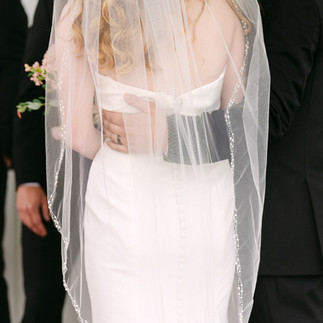 Close-up of bride and groom holding each other during ceremony, sheer veil and delicate details captured in soft natural light.