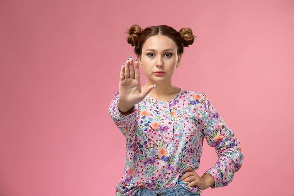 front-view-young-female-flower-designed-shirt-blue-jeans-showing-stop-sign-pink-background