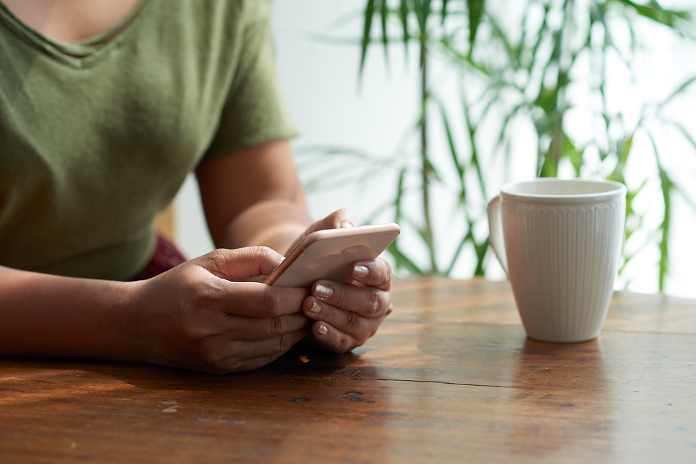 Pessoa segurando celular sobre a mesa com uma xícara ao lado, representando o registro de mensagens de condomínio pelo WhatsApp.