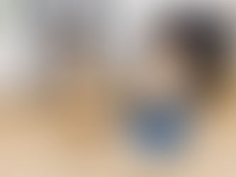 A dog standing alongside a girl sitting on the floor working on a laptop