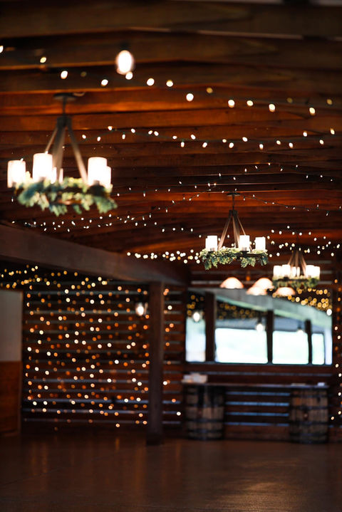 Dimly lit rustic reception space with chandeliers, wooden walls, and cake table for 200 guests at wedding venue near Houston, Texas, ideal for elegant and intimate celebrations