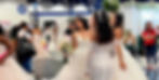 Brides in elegant dresses converse in a bustling bridal expo, surrounded by attendees at the Houston Bridal Extravaganza in Houston Texas