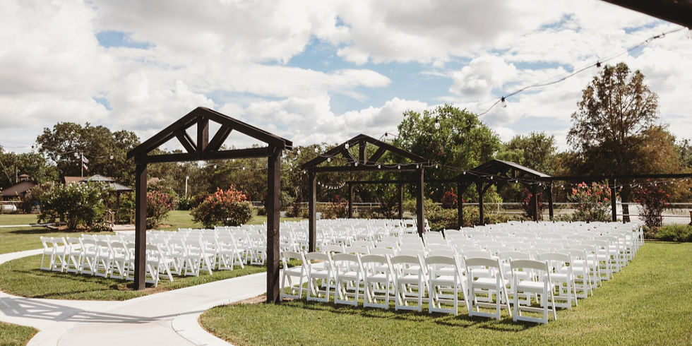 Outdoor wedding venue near Sugar Land, Texas with rows of empty white chairs and wooden arches on a grassy field under cloudy blue skies, evoking a peaceful mood.
