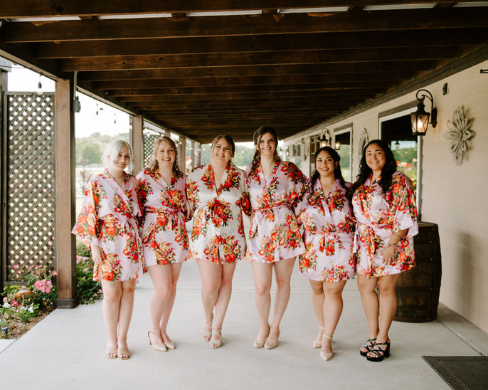 A brides and bridesmaids enjoying the morning of the wedding day in their pajamas posing at a wedding venue's front porch at a wedding venue near Houston, Texas.