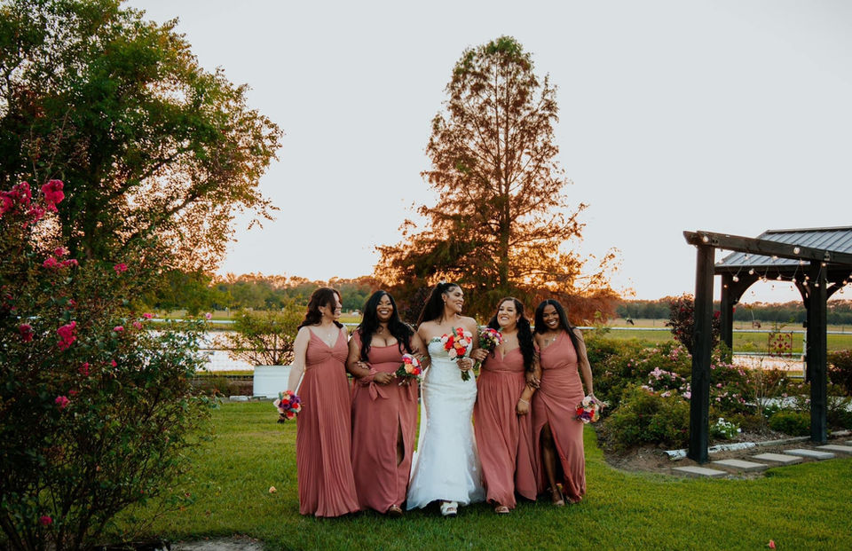 Bridal party smiling and posing in a rose garden near Sugar Land surrounded by vibrant blooms