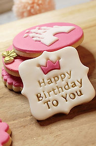 Sablés décorés artisanaux pour anniversaire de petite fille, thème princesse avec couronnes en relief et message Happy Birthday, pâte à sucre rose et blanche, création Biscuit Signature à Tarare