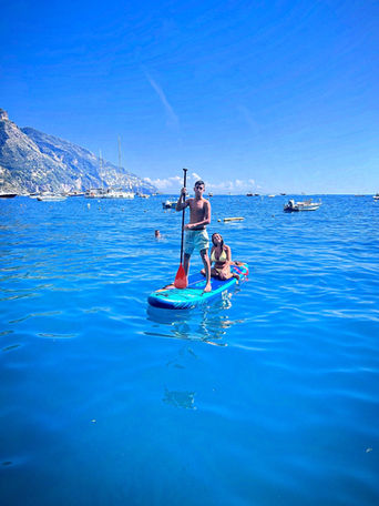 Couple paddleboarding on the water with clear blue skies Sup Club Positano