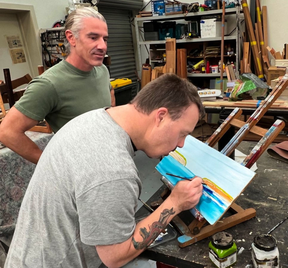 Jason paints a scenic landscape at Langwarrin Men's Shed