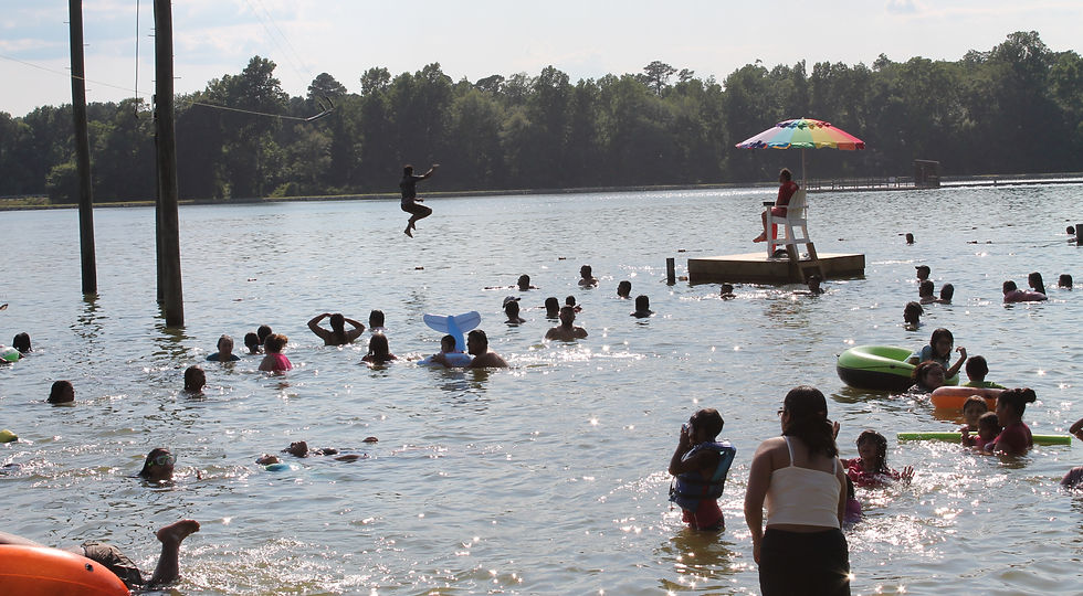 Crowded lake with swimmers, a lifeguard, and person jumping from height.