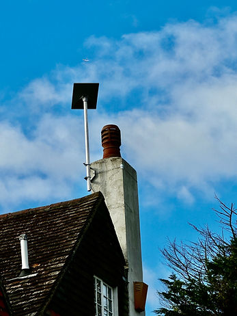 A Starlink receiver installed on an external chimney with a blue sky in the background