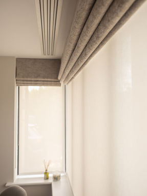 Close up of an automated Roman blind in a neutral fabric within a bedroom