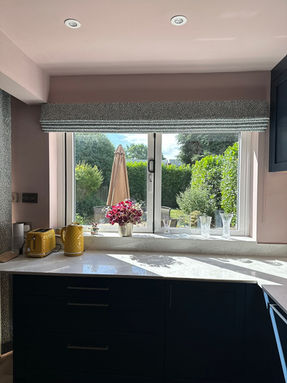 roman blind in a green and white wiggly lined design in a kitchen
