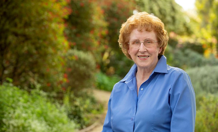 Headshot of Pat Stroberg in blue button-up in front of green nature