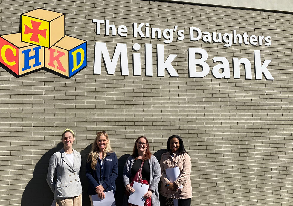 A diverse group of women stand outside of a sunlit brick building labled "Children's Hospital of the King's Daughters Milk Bank"