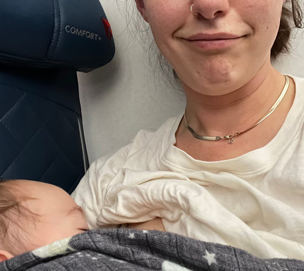 A mother is breastfeeding a baby in an airplane seat.