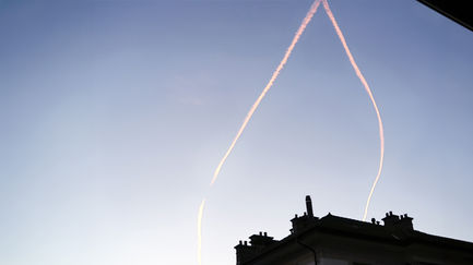 Silhouette of a building with sky contrails above.