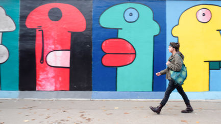 Colorful abstract mural with person walking by.